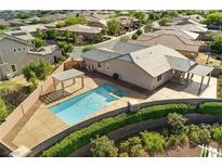 Backyard view of in-ground pool with tanning deck and covered patio with built-in bbq, landscaping, and neighborhood view at 10302 Artful Stone Ave, Las Vegas, NV 89149
