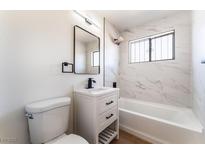 Modern bathroom with a white vanity, sleek black fixtures, and marble-look tile surrounding the bathtub at 1648 J St, Las Vegas, NV 89106