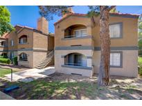 Two-story condo with a stucco exterior, gray accents, and a staircase leading to the upper level at 220 Mission Newport Ln # 105, Las Vegas, NV 89107