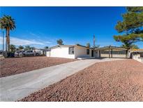 Single-story home featuring a gravel front yard, long driveway, and covered carport against a clear, blue sky at 2878 El Cajon St, Las Vegas, NV 89169