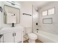 Modern bathroom featuring white vanity with a dark faucet, framed mirror, and tiled shower-tub at 3309 Marionette Ave, Las Vegas, NV 89101