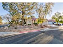 Charming single-story home featuring a landscaped front yard with mature trees and a two-car garage at 5601 Cavalier Cir, Las Vegas, NV 89130