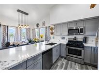 Modern kitchen featuring gray cabinetry, stainless steel appliances, and a breakfast bar overlooking the living area at 7241 Indian Creek Ln # 203, Las Vegas, NV 89149