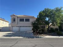 Two-story home with a three car garage, red tile roof, and lush landscaping in a sunny neighborhood at 7416 Alcove Glen Ct, Las Vegas, NV 89129