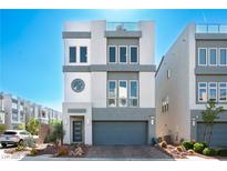 Modern three-story home featuring a gray garage door, drought-tolerant landscaping, and a small rooftop deck at 8175 Caldera Creek St, Las Vegas, NV 89113