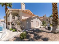 Condo building exterior with stairs, desert landscaping, and visible community pool at 1013 Falconhead Ln # 202, Las Vegas, NV 89128