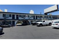A white two-story building featuring exterior stairs and arched driveway entrance with parked trucks and cars at 4600 Paradise Rd # 16, Las Vegas, NV 89169