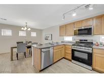 Bright eat-in kitchen featuring stainless steel appliances, light wood cabinetry, and a modern dining area at 6048 Aripeka St, Henderson, NV 89011