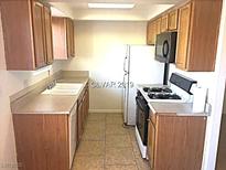 Traditional kitchen with white appliances and wood cabinets for a classic look at 8417 Running Deer Ave # 101, Las Vegas, NV 89145