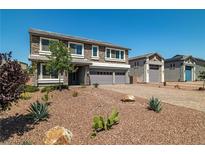 Beautiful two-story home featuring a stone facade, three-car garage, and desert landscaping at 8753 Mann St, Las Vegas, NV 89139
