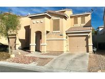 Two-story home with an attached garage, desert landscaping, and a covered entryway at 1676 Buck Island St, Las Vegas, NV 89156