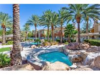 Community pool and spa area with palm trees, waterfall features, and lounge chairs at 10640 Amber Ridge Dr # 101, Las Vegas, NV 89144