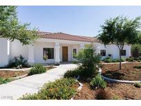 Charming single-story home featuring a tile roof, landscaped yard, and a welcoming front porch with classic column supports at 7745 Radcliff St, Las Vegas, NV 89123