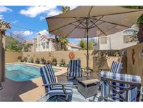 Inviting backyard pool area with comfortable seating and shaded umbrella for relaxation at 1604 Imperial Cup Dr, Las Vegas, NV 89117