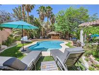 Backyard pool featuring lush tropical landscaping, a swim-up bar, lounge chairs, and a beautiful patio area at 2608 Prospector Mine Ave, North Las Vegas, NV 89031