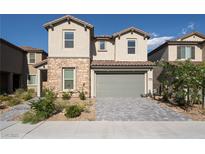 Charming two-story home with stone accents, desert landscaping, a gray two-car garage door, and a paver driveway at 6486 Vanhoven Crest St, Las Vegas, NV 89166
