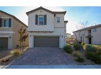 Charming two-story home featuring a neatly landscaped front yard and a two-car garage with a brick driveway at 7037 Tilligerry St, North Las Vegas, NV 89084