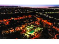 Night aerial view of a well-lit community with a pool and a distant city skyline at 1557 Blue Sierra Ct, Henderson, NV 89074
