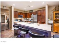 Modern kitchen features dark wood cabinets, stainless appliances, and a spacious white quartz island with bar seating at 1557 Blue Sierra Ct, Henderson, NV 89074