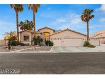 Inviting single-story home with a neutral-colored exterior, palm trees, and a spacious three-car garage at 303 Hidden Highlands Dr, Las Vegas, NV 89110
