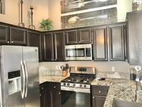 Modern kitchen features stainless steel appliances, dark cabinetry, and granite countertops at 3329 Hidden Ridge St, Las Vegas, NV 89129