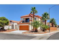 Two-story home featuring a charming front balcony, desert landscaping, and an orange garage door at 6652 Coral Springs Cir, Las Vegas, NV 89108