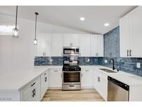 Modern kitchen featuring stainless steel appliances, white cabinets, and stylish blue backsplash at 116 Lotus Blossom Ct, Las Vegas, NV 89145