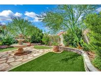 Beautiful backyard with a stone fountain, artificial grass, mature trees and landscaping at 326 Caneflower Ct, North Las Vegas, NV 89031