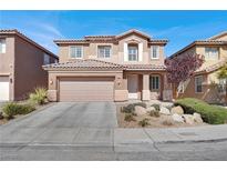 Charming two-story home featuring a tile roof, tan exterior, and a two-car garage, complemented by a landscaped front yard at 4036 W Bird Man Ln, North Las Vegas, NV 89084