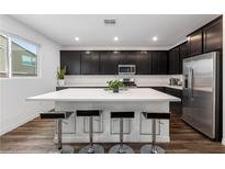 Modern kitchen boasts a large island with bar seating, dark cabinetry, and stainless steel appliances at 4348 Bayley Skye Ave, Las Vegas, NV 89141
