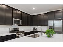Modern kitchen featuring stainless steel appliances and dark cabinets with white countertops at 4348 Bayley Skye Ave, Las Vegas, NV 89141