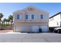 Two-story tan home featuring a three-car garage and tidy landscaping at 6459 Rusticated Stone Ave # 103, Henderson, NV 89011