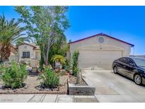 Charming single-story home with a two-car garage, desert landscaping, and mature trees, providing curb appeal at 2402 Saguaro Point St, Las Vegas, NV 89115