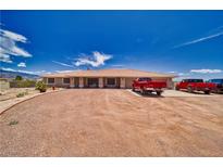 Expansive single-story home boasts a large gravel driveway and inviting curb appeal under a clear blue sky at 3251 S Parkridge Ave, Pahrump, NV 89048