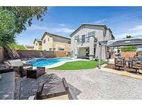 Inviting backyard featuring a pool, artificial grass, and comfortable seating areas, perfect for relaxation and entertaining at 3591 Gloucester Gate St, Las Vegas, NV 89122