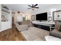 Inviting living room with a plush rug, modern ceiling fan, and large screen television at 5131 Moose Falls Dr, Las Vegas, NV 89141
