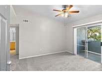 Bright bedroom featuring neutral carpet, sliding glass door, and ceiling fan with light fixture at 6955 N Durango Dr # 2054, Las Vegas, NV 89149