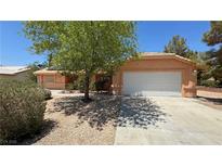Charming single-story home featuring a two-car garage, landscaped front yard, and mature tree at 710 Tomahawk Ct, Pahrump, NV 89060