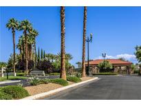 Gated community entrance featuring lush landscaping and mature palm trees under a clear blue sky at 7889 Rancho Mirage Dr, Las Vegas, NV 89113