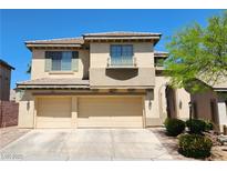 Tan two-story home featuring a three-car garage and desert landscaping under a clear blue sky at 9052 Pine Mission Ave, Las Vegas, NV 89143
