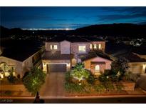 Stunning two-story home with lush landscaping and a view of the Las Vegas skyline at night at 29 Costa Tropical Dr, Henderson, NV 89011