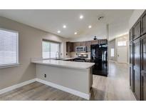 Open kitchen boasts stainless appliances, brown cabinetry, recessed lighting, and a breakfast bar at 87 Ginger Lily Ter, Henderson, NV 89074