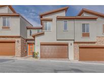 Modern townhomes with stone accents, brown garages, and eye-catching orange front doors at 11922 Glide Reflection Ave, Las Vegas, NV 89138