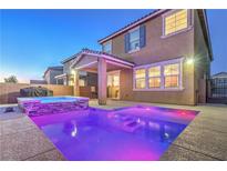 Backyard view of a stunning pool and hot tub illuminated at twilight and covered patio of home at 2787 Donatello Manor Pl, Henderson, NV 89044