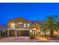 Elegant two-story home featuring a three-car garage, arched entry, stone accents, and lush palm tree in landscaped yard at 4045 Abernethy Forest Pl, Las Vegas, NV 89141