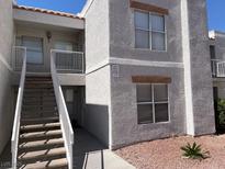 Two-story condo featuring a staircase leading to the upper units, neutral stucco, and well-maintained landscaping at 6800 E Lake Mead Blvd # 2024, Las Vegas, NV 89156