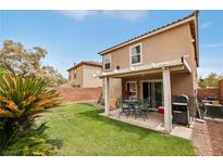 Outdoor living space with covered patio, lush lawn, and a dining set at 11620 Longhirst Hall Ln, Las Vegas, NV 89138