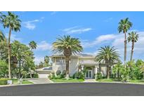 Stately stucco home featuring lush landscaping, a circular driveway, and ample palm trees at 3372 Westwind Rd, Las Vegas, NV 89146