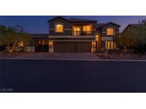 Elegant two-story home featuring a private balcony, well-manicured landscaping, and a spacious three-car garage at twilight at 3934 Sangre De Cristo Ave, Las Vegas, NV 89118