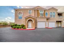 Two-story stucco townhome featuring attached garages, manicured landscaping, and private entrance at 10001 Peace Way # 2322, Las Vegas, NV 89147